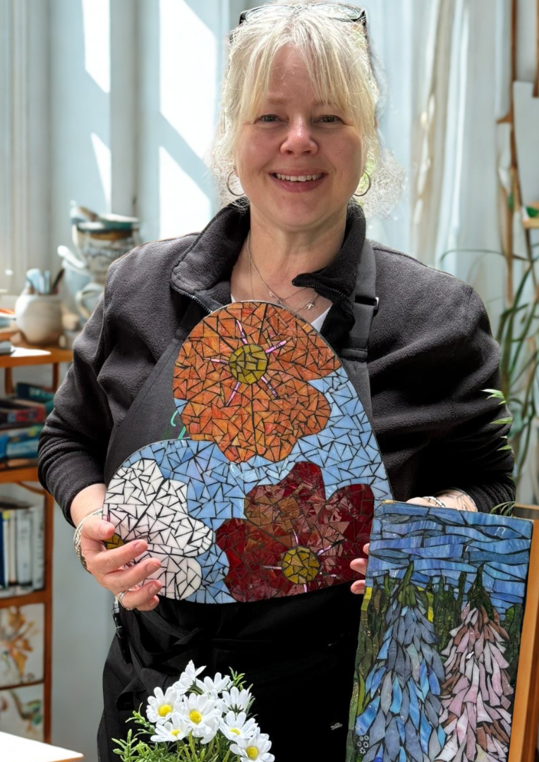 Jenni holding a colourful flower mosaic in her garden